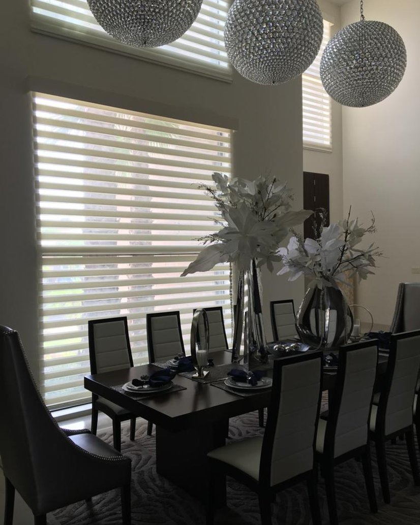 dual sheer shades on floor-to-ceiling windows in a dining room with crystal chandeliers