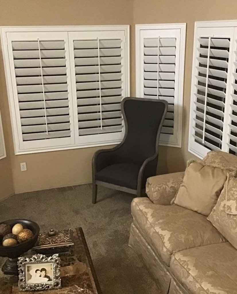 white plantation shutters across four windows in a living room