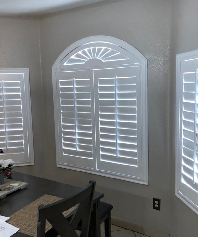 white plantation shutters with arched sunburst window in a breakfast nook