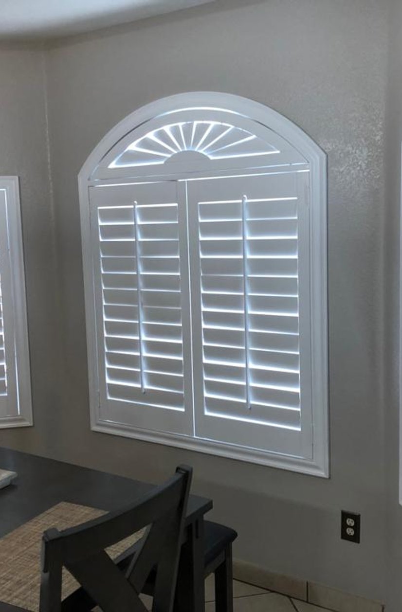 white plantation shutters with arched sunburst window in a breakfast nook