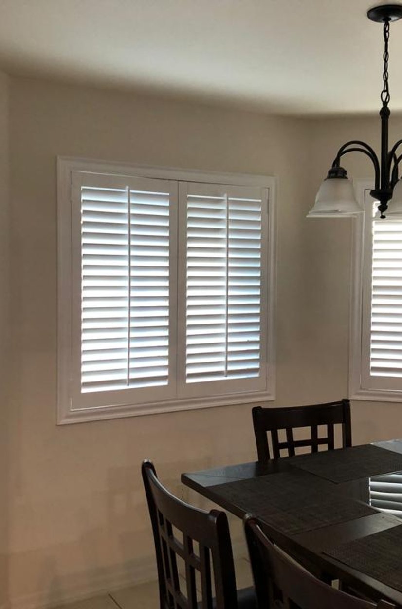 white plantation shutters across a bay window in a dining room